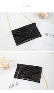 Detailed view of the shiny black crocodile texture and golden chain on this fashion envelope bag