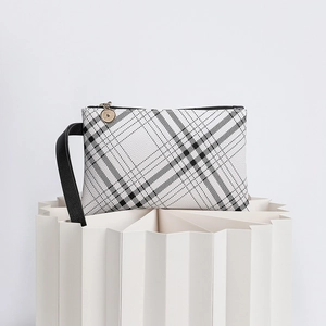 Detail of minimalist striped clutch bag with gold round zipper pull and black strap