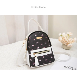 Close-up of mini floral backpack with pink patterns and metal logo plate on white table