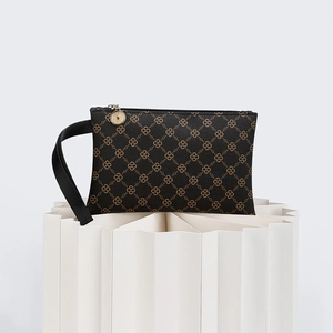 Detail of dark brown clutch bag with geometric gold logo print and metal zipper closure