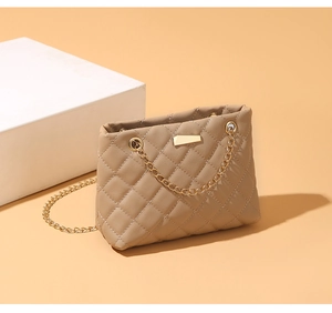 Detail of khaki quilted shoulder bag with gold chain strap and rectangular metal hardware