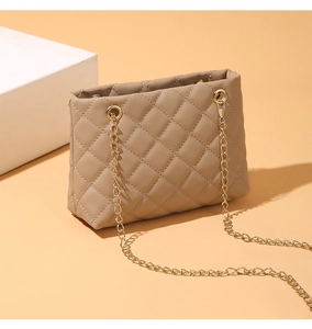 Detailed close-up of beige quilted leather texture and golden metal chain strap