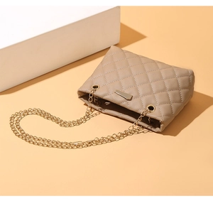 Close-up of beige quilted texture and gold chain detail on women luxury shoulder bag
