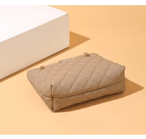 Close-up of quilted beige chain bag with elegant diamond stitching and gold metal hardware