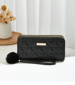 Detail of black quilted leather long wallet with double zippers and pompom wristlet