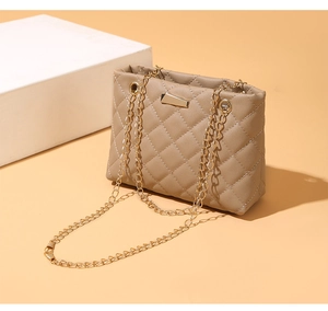 Detail of quilted stitching texture and gold chain on elegant taupe shoulder bag