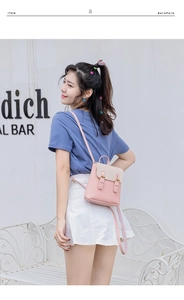 Detailed outdoor view of pink and beige mini backpack with metal buckle and top handle
