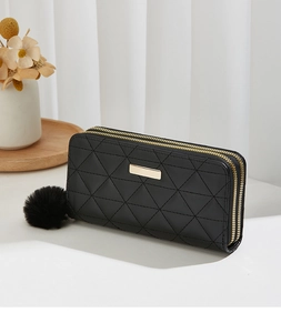 Detail of black long wallet featuring geometric quilted texture and gold metal plaque
