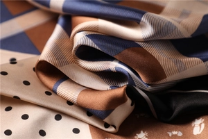 Close-up of a satin scarf with paisley patterns, polka dots, and cat illustrations