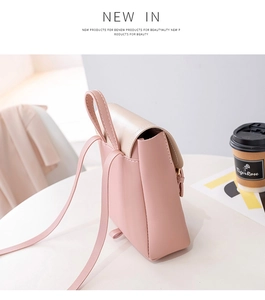 Detail view of pink and beige mini backpack showing stitching and handle on a table