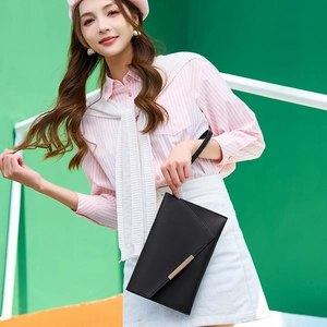 Minimalist black envelope clutch bag with gold metal trim and wristlet strap for women