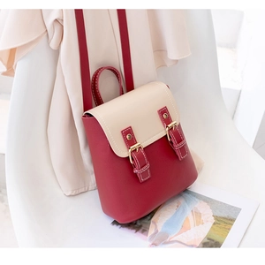 Detailed view of mini red and cream backpack with vintage buckles on a white chair