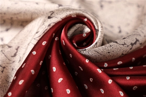 Macro shot of paisley silk scarf showing glossy satin texture and two-tone pattern detail