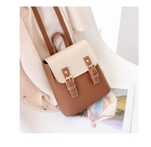 Detail of a two-tone mini backpack showing beige flap with brown double buckle straps
