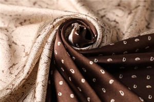 Detail of silk-like paisley scarf with two-tone beige and brown floral pattern texture