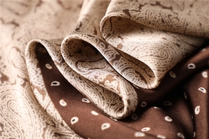 Macro shot of paisley patterned silk scarf with premium brown satin texture and soft drapes