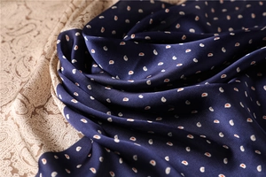Macro shot of smooth navy silk scarf fabric featuring detailed red and white paisley patterns