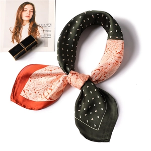 Detail of green and orange paisley silk scarf styled in a decorative knot