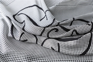 Macro detail of houndstooth silk scarf with elegant black artistic letter printing