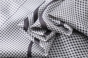 Macro detail of houndstooth silk scarf showing soft texture and glossy black white patterns