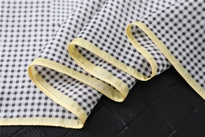 Close-up of black and white houndstooth silk scarf with yellow stitched hem detail