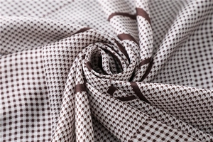 Macro shot of houndstooth silk scarf showing shiny smooth texture and brown pattern