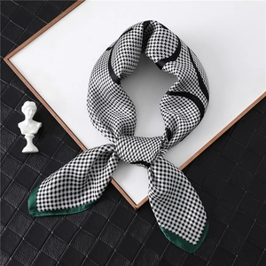 Elegant houndstooth silk scarf with green satin border displayed on a premium black background