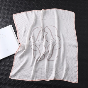 Detail of silk scarf showing white houndstooth texture with pink border and logo