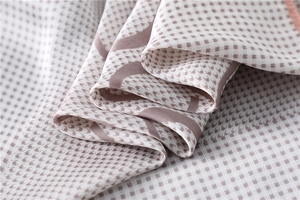 Macro detail of houndstooth silk scarf showing smooth texture and fine rolled edges