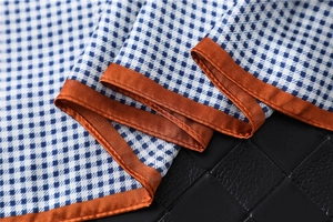 Detail of blue houndstooth faux silk scarf with elegant caramel satin edge finish