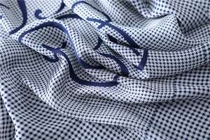 Detail of silk-like houndstooth scarf with blue letter print and soft fabric folds