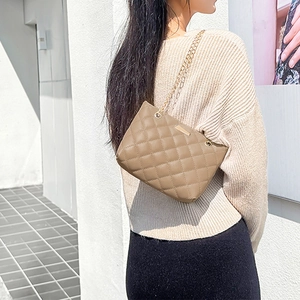 Elegant quilted crossbody bag in khaki finish with gold chain strap shown on shoulder