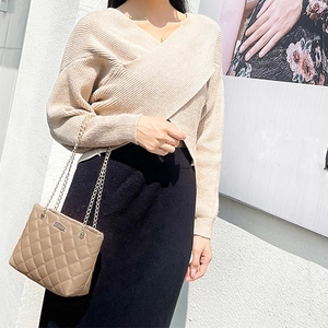 Elegant quilted khaki chain bag paired with a beige V-neck knit top and black midi skirt