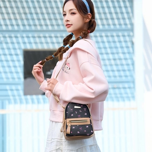Mini backpack crossbody with floral prints and bow detail worn by a model in pink hoodie