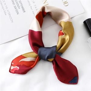 Detailed view of geometric silk scarf with red, yellow, and navy patterns and rolled edges