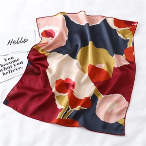Detail of floral silk square scarf with satin finish and rolled edges on white fabric