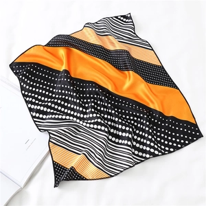 Detail of silk-like orange and black polka dot scarf folded on a white book