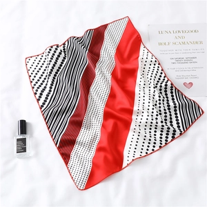 Detail of red and black silk scarf with stripes and polka dots on white background