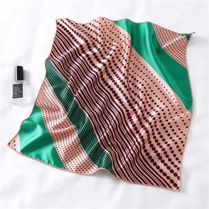 Detail of square silk scarf with polka dots and stripes on a satin finish surface