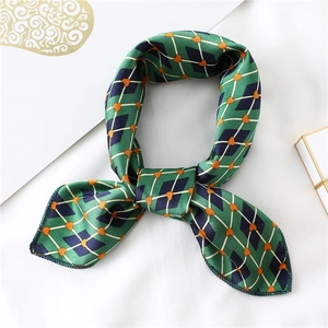 Detail of green silk-like satin scarf with blue rhombus and orange heart patterns