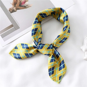 Detail of yellow and blue geometric silk scarf tied in an elegant knot on white desk
