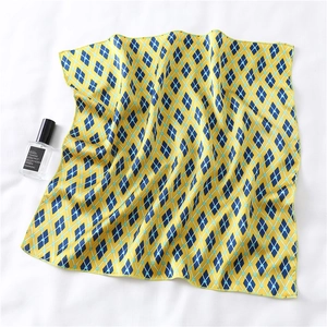 Detail of yellow and blue argyle silk scarf with refined edges on white fabric background
