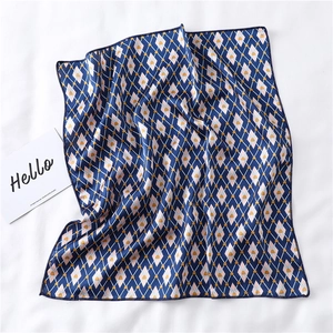 Macro shot of square silk scarf with blue and pink geometric diamond patterns and fine hem
