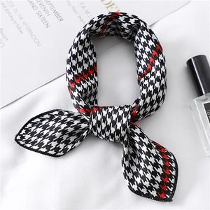 Close-up of houndstooth silk scarf with red stripe accent and satin texture finish