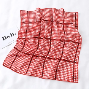 Detail of red and white houndstooth square scarf with black grid and fine red stitching