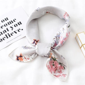 Detail of light grey floral silk scarf tied in a bow knot with delicate hemmed edges