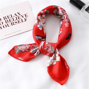 Close-up of red floral silk scarf tied in a bow on soft white fabric background