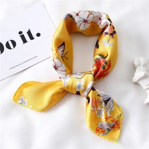 Detail of yellow silk scarf featuring white floral and butterfly prints with silk texture
