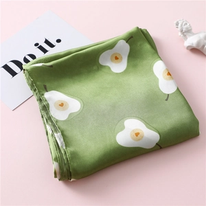 Dettaglio del foulard in seta verde muschio con stampa a pera bianca e cuore arancione