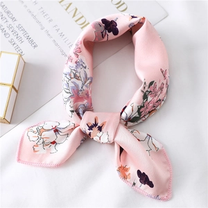 Close-up of elegant pink floral silk scarf with smooth satin texture and refined knotting